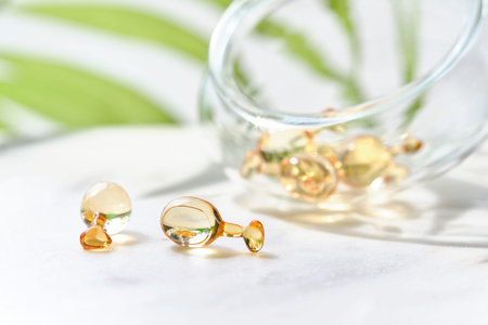 Serum capsules for healthy skin. Close-up on transparent bottle with the capsules. Green palm leaf.