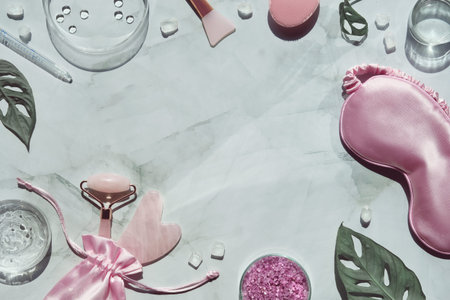 Home made moisturizer, pink quarz face roller and guasha stone, pipette on off white marble...