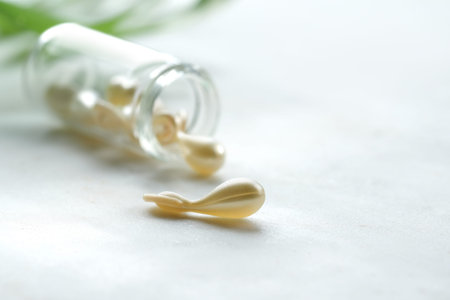 Serum capsules for healthy skin. Close-up on transparent bottle with metallic golden capsules.