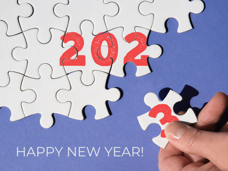 Jigsaw puzzle with numbers 2023, hand with missing piece, fingers add number 3 together with linked...