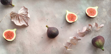 Fresh halved fig fruits and dry euvalyptus and cala lily flowers painted metallic pink on bstract textured background.の写真素材