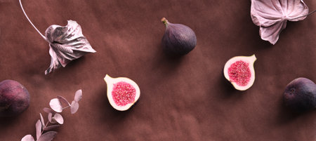 Fresh halved fig fruits and dry euvalyptus and cala lily flowers painted metallic pink on bstract textured background.の写真素材