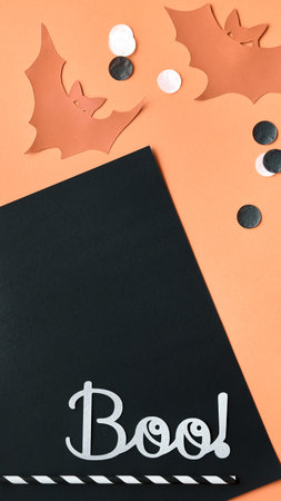 Cute Halloween vertical background, monochromatic orange template for social media stories. Orange black background with black white paper confetti, copy-space. Paper bat silhouettes.の写真素材