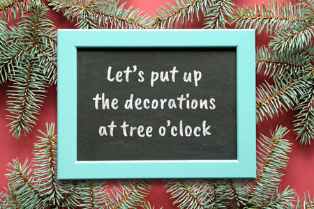 Red green Christmas background with fir twigs. Copy-space on blackboard, chalk board in wood frame.