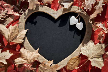 Heart shaped letter board, blackboard with heart trinkets. Dry Autumn leaves, natural Fall decor on crumpled red paper background. Copy-space, place for your greeting text. Flat lay, top view.の写真素材