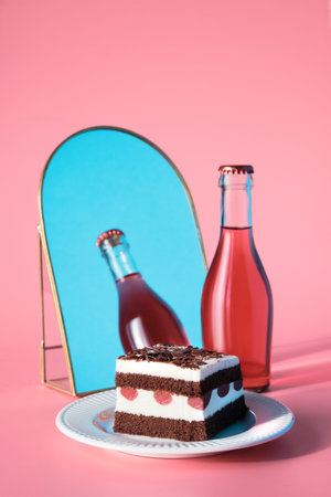 Chocolate cake with sour cherries. Piece of cake on a plate with fork. Sweet dessert and rosa vine on pink background with blue sky reflected in arch mirror.の写真素材