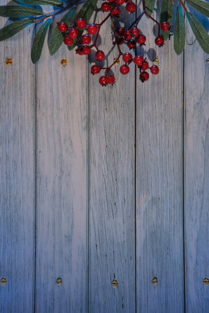 Wintertime rustic background with decorative rowan berry twigs with green leaves and red berry. Flat lay, top view, space for text, copy-space on wooden planks.の写真素材