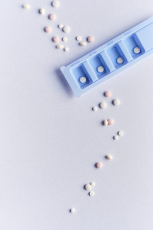 Tablet, pill dispenser and tablets. Flat lay, top view on off white backgrund.
