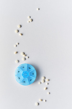 Tablet, pill dispenser and tablets. Flat lay, top view on off white backgrund.