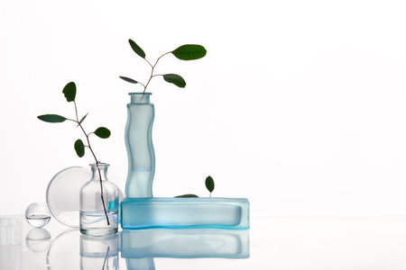 Monochromatic Surrealism - Transparent Flask and Water-filled vases with Eucalyptus on Glass Tableの写真素材