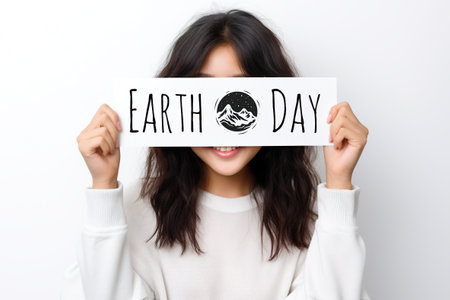A woman holding a sign that says earth day. Generative AI image.の素材