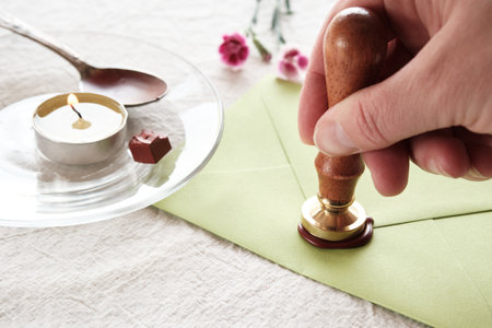 Envelope wax seal with carnation flowers on white table.の写真素材