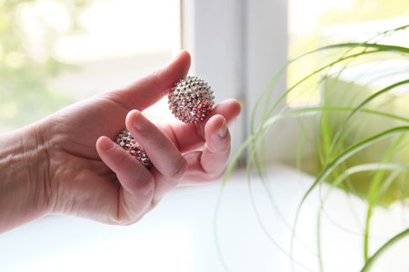 Silver metal magnetic balls in female hand. Spiky tool for hand massageの写真素材