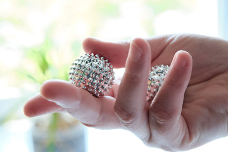 Silver metal magnetic balls in female hand. Spiky tool for hand massage. Close-up on middle-aged hand.の写真素材