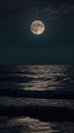 A full moon rising over the ocean on a dark nightの素材