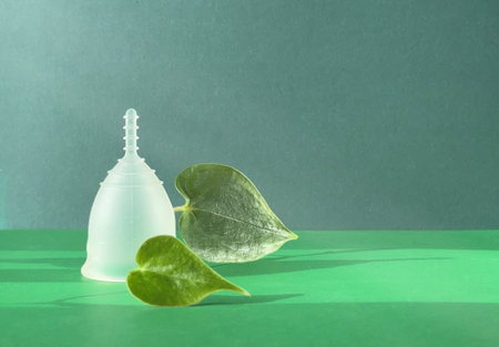 Reusable Menstrual Cup With Green Leaf on Green Colored Paperの写真素材