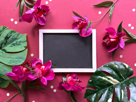 Vibrant Tropical Flowers Surrounding Blank Chalkboard on Pink Polka Dot Backgroundの写真素材
