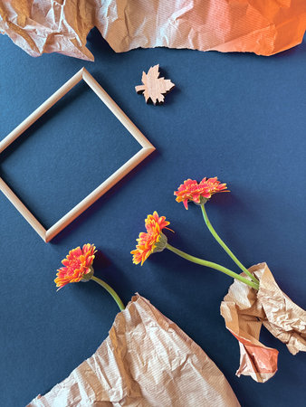 Autumn Floral Composition with Wooden Frame, Orange Flowers, and Paper Wrapping on Black Surface