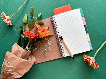 Open Notebook with Pen and Flowers on Green Background - Creative Workspace Essentialsの写真素材