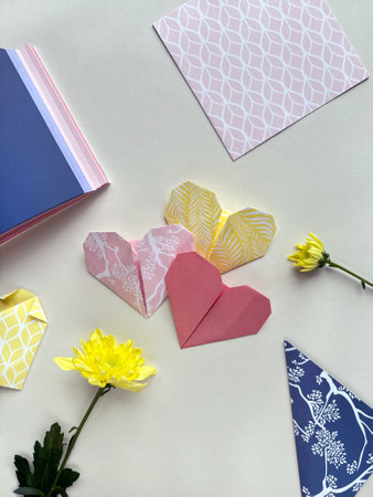 Colorful Origami Hearts and Patterned Paper with Yellow Chrysanthemums on Neutral Backgroundの写真素材
