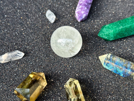Various Gemstones on Black Sand Background Displaying Different Colors and Shapes
