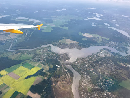 Aerial perspective over Berlin, Germany featuring a scenic view of rural landscapes, rivers, and patchwork fields. Airplane wing visible in the foreground.の写真素材