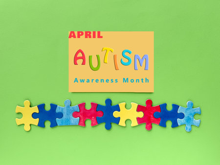 Autism Awareness Month design featuring colorful interlocking puzzle pieces on a green background. Includes text "April Autism Awareness Month" in vibrant colors.の写真素材