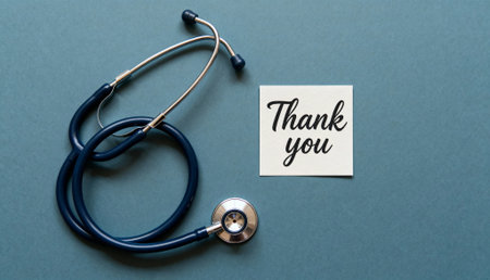 Stethoscope placed on a blue surface next to a handwritten note saying "Thank you," symbolizing appreciation for medical professionals and healthcare workers.の素材
