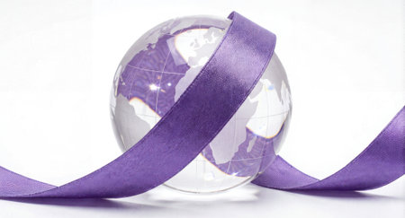 Glass globe wrapped by a purple satin ribbon on a clean white background with generous empty space for text and branding. The minimalist composition conveys global concepts, celebration, charity, and corporate messagingの素材