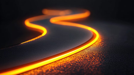 A captivating image of a glowing orange line that elegantly winds its way across a dark surface. The contrast between the vibrant light and the shadowy background creates a striking visual that draws the eye and evokes a sense of movement and energyの素材