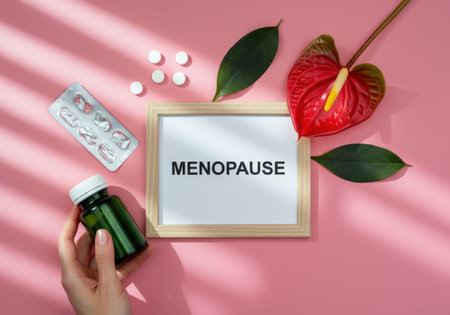 A visually appealing arrangement featuring a hand holding a green supplement bottle, surrounded by pills, a framed sign reading MENOPAUSE, and a vibrant plant. This image highlights the importance of health and wellness during menopauseの素材