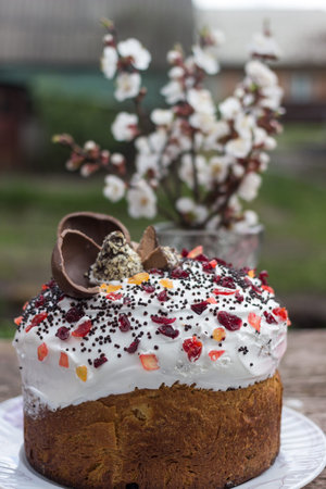 A beautiful, large, family Easter cupcake on a wooden texture table with a bouquet of cherry...