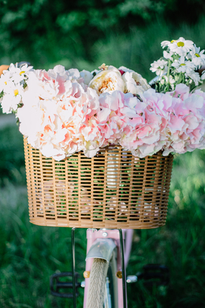 Beautiful sping flowers in a wicker bicycle basketの写真素材