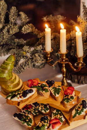 christmas dinner with candles. Italian bruschetta with cream cheese, strawberry, arugula and balsamic vinegar sauce with honeyの写真素材