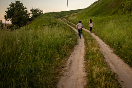 a man and a girl in rustic clothes run along a village road.の写真素材
