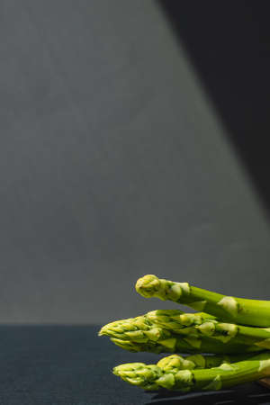 branches of fresh green asparagus on a wooden board, dark gray background, top view. Basic trend concept with copy space.の写真素材