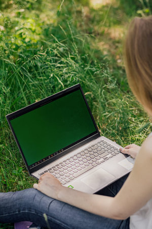 girl sits on the grass and works at a laptop. freelance. self-education. the concept of distance...