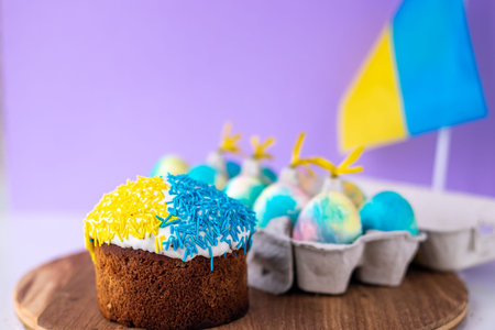 Easter cake decorated in colors of Ukrainian flag and eggs painted in yellow blue, laid out around...