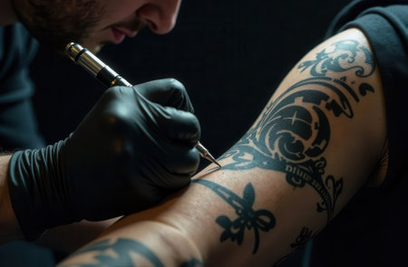 Caucasian male tattoo artist creating detailed arm ink design.の写真素材