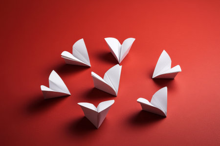 Origami paper butterflies in circular formation on red background.の写真素材