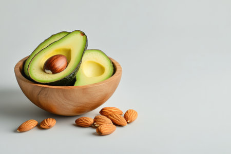 Fresh avocado halves in wooden bowl with almonds on light background.の写真素材