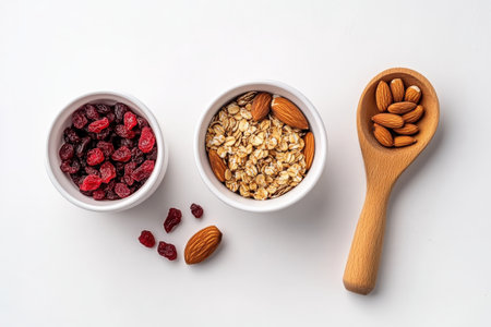 Healthy breakfast ingredients: dried cranberries, rolled oats, almonds in white bowls and wooden spoon.の写真素材