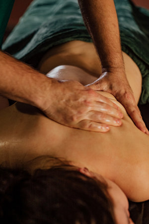 Professional massage therapy session with male therapist and relaxed female client.の写真素材