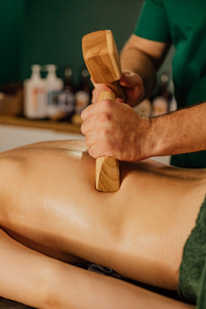 Therapeutic massage with wooden tool on female adult at spa setting.の写真素材