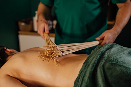 Asian adult male undergoing relaxing bamboo massage therapy session.の写真素材