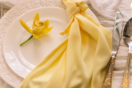 Elegant table setting with yellow orchid and gold flatware.