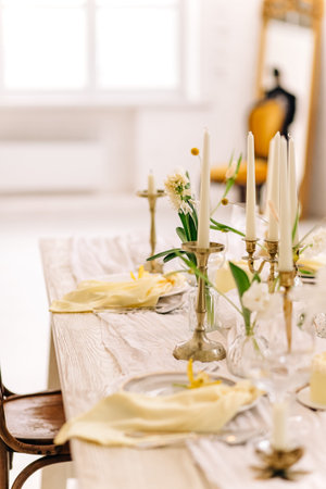 Elegant table setting with candles and flowers in bright dining room.