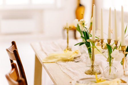Elegant spring table setting with candles and flowers in a sunny dining room.の写真素材