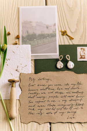 Vintage love letter on rustic table with earrings and floral decor.の写真素材