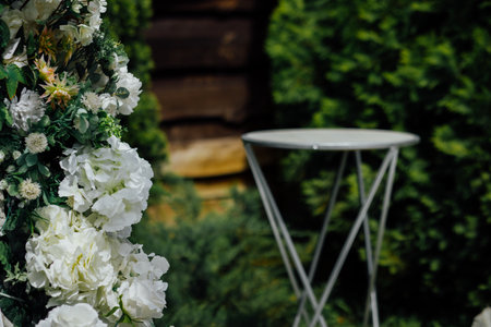 Outdoor garden setting with white floral decoration and metal table.の写真素材